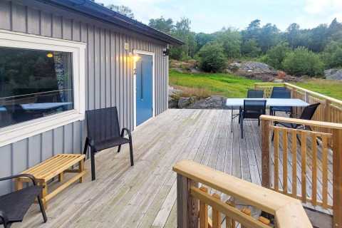 Træterrasse med havemøbler foran en hytte i Nösund, Sverige, omgivet af natur og grønne træer.