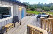 Ruim houten terras met stoelen en tafel aan een 4-persoons vakantiehuis in Nösund, Zweden.
