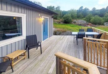 Grande terrasse en bois avec chaises devant un chalet de 4 personnes à Nösund, Suède, en pleine nature.