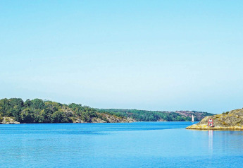 Wunderschöner Ausblick auf das Wasser bei Nösund, Schweden, mit Segelboot und grüner Küstenlandschaft.