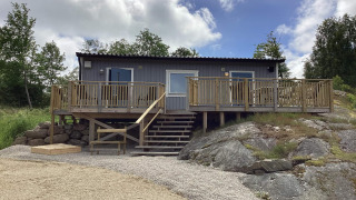 Maison de vacances pour 4 personnes à Nösund, terrasse en bois, escaliers et paysage rocheux sous ciel nuageux.