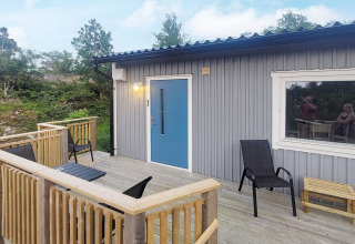 Houten terras bij een vakantiehuis in Nösund, Zweden, met stoelen, tafel en uitzicht op de natuur.