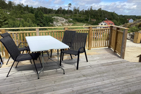 Terrasse extérieure avec table et chaises dans un chalet à Nösund, Suède, vue sur la nature et des maisons.