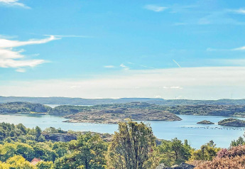 Udsigt over smukke søer, øer og grøn natur fra en feriebolig i Nösund, Sverige, under en klar blå himmel.