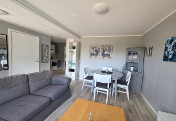 Stue i 4-personers feriehus i Nösund, Sverige, med grå sofa, spisebord og moderne indretning.
