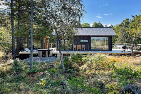 Maison de vacances 4 étoiles à VÄDDÖ, grande terrasse en bois, nature environnante et jacuzzi extérieur.