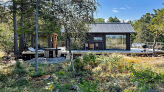 Hyggeligt sommerhus i VÄDDÖ omgivet af natur med stor træterrasse, spabad og havemøbler i solen.