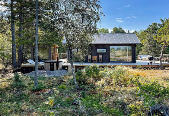 Viersterren vakantiehuis in VÄDDÖ met groot houten terras, bosrijke omgeving en buitenzitje.