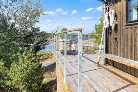 Houten terras met uitzicht op water en bos bij een hut in VÄDDÖ, Zweden op een zonnige dag.