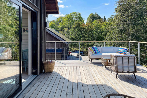 Udendørs terrasse på en moderne hytte i VÄDDÖ, Sverige, med kurvemøbler og farverige puder.
