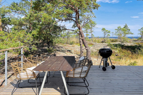 Buitenterras met eettafel en barbecue in de natuur bij de 4 star holiday home in VÄDDÖ, Zweden.