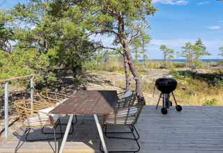 Espace repas extérieur avec barbecue sur terrasse en bois, vue nature au 4 star holiday home in VÄDDÖ, Suède.