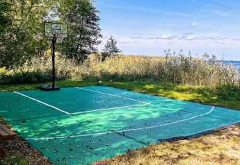 Terrain de basket extérieur près d’un lac à 4 star holiday home in VÄDDÖ, Suède, entouré de verdure.