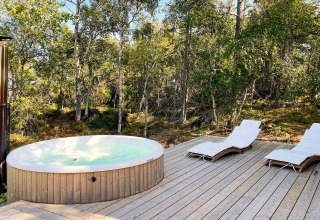 Bain à remous extérieur et transats sur terrasse en bois près de la forêt à '4 star holiday home in VÄDDÖ', Suède.