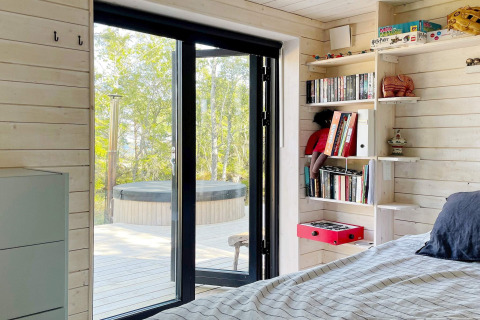 Slaapkamer in een vakantiehuis in Väddö, Zweden met uitzicht op het terras en bubbelbad buiten.