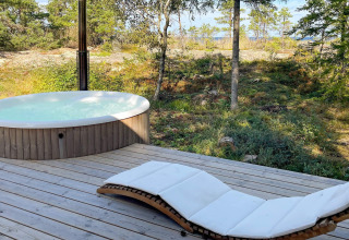 Terrasse en bois avec bain à remous rond et transat blanc, entourée de nature suédoise à Väddö.