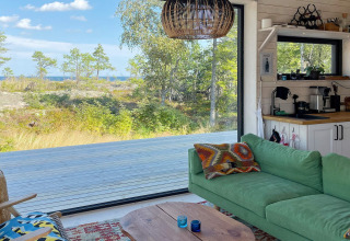 Gezellige woonkamer in een 4-sterren vakantiehuis op VÄDDÖ, Zweden, met groene bank en natuurzicht.