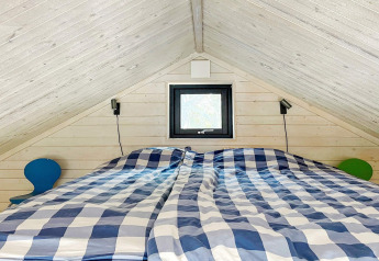 Bedroom in a cabin in VÄDDÖ, Sweden, featuring a sloped ceiling, checkered bedding and small tables.