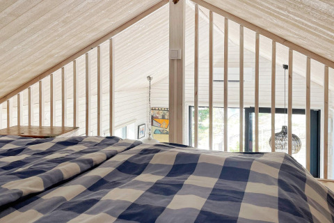 Vista desde el altillo de un acogedor alojamiento en VÄDDÖ, Suecia, con ropa de cama a cuadros azules.