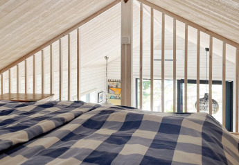 Vista desde el altillo de un acogedor alojamiento en VÄDDÖ, Suecia, con ropa de cama a cuadros azules.