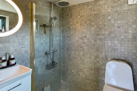 Bagno moderno in una casa vacanze a VÄDDÖ, Svezia, con doccia, WC e pareti piastrellate.