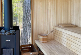 Moderne sauna met houten interieur, Harvia-kachel en uitzicht op bos in vakantiehuis in VÄDDÖ, Zweden.