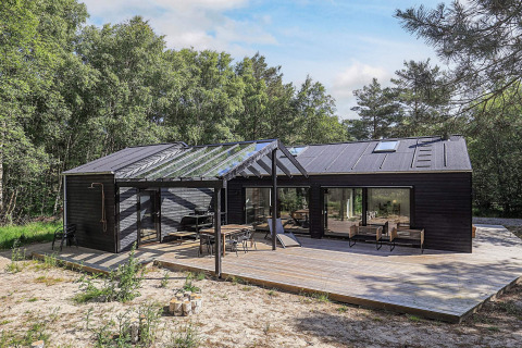 Casa vacanze a cinque stelle a Læsø con ampia terrazza in legno e moderna copertura in vetro.