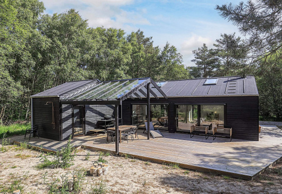 Luxe vijfsterren vakantieverblijf op Læsø met ruime houten vlonder en uitzicht op het bos.
