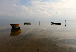Trois bateaux se reflètent sur l’eau calme près de 5 star holiday home à Læsø, Danemark, sous un ciel nuageux.