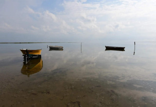 Tres barcos reflejados en aguas tranquilas junto a 5 star holiday home en Læsø, Dinamarca, bajo cielo nublado.