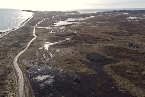 Vue aérienne de Læsø avec une route côtière sinueuse, zones humides et mer près d'un gîte 5 étoiles.