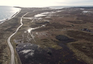 Vue aérienne de Læsø avec une route côtière sinueuse, zones humides et mer près d'un gîte 5 étoiles.