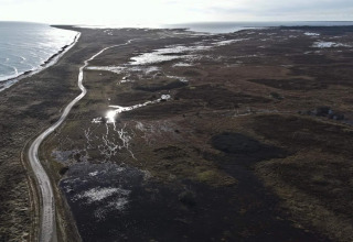 Luftfoto af Læsø med snoet vej langs kysten, vådområder og havudsigt nær 5-stjernet feriebolig.