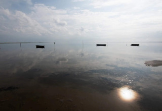 Calm water reflecting sky and boats near the horizon at 5 star holiday home in Læsø, Denmark.