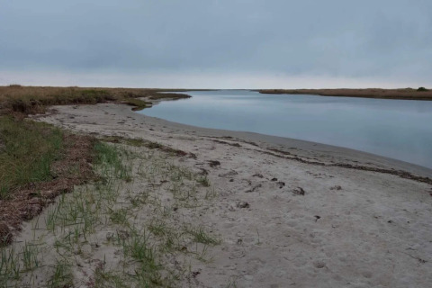 Ruhiger Flusslauf an einem Sandstrand bei der 5-Sterne-Ferienwohnung in Læsø, Dänemark unter bewölktem Himmel.