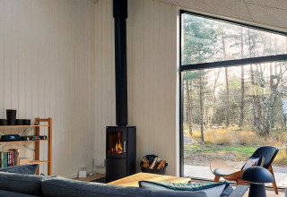 Salon lumineux et moderne dans maison de vacances 5 étoiles à Læsø, Danemark, avec poêle et baie vitrée.