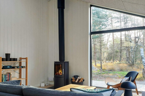 Salon lumineux et moderne dans maison de vacances 5 étoiles à Læsø, Danemark, avec poêle et baie vitrée.