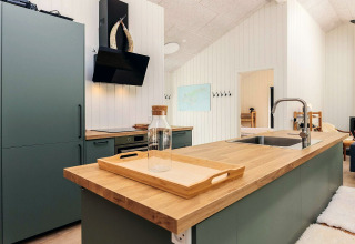 Cuisine moderne d'une maison de vacances 5 étoiles à Læsø, Danemark, avec plan de travail en bois.