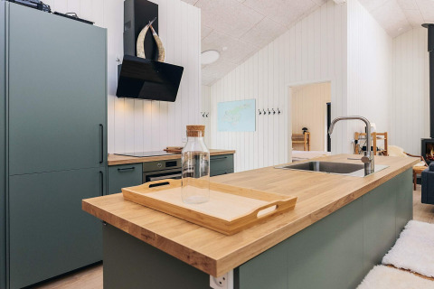 Cuisine moderne d'une maison de vacances 5 étoiles à Læsø, Danemark, avec plan de travail en bois.