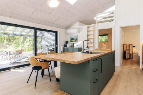 Moderne køkken og spiseområde i et feriehus på Læsø, Danmark, med udsigt til terrasse og natur.