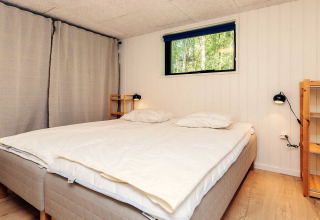 Chambre dans une maison de vacances 5 étoiles à Læsø, Danemark, avec lit double et étagères bois.