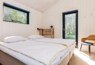 Chambre lumineuse dans une maison de vacances à Læsø, Danemark, avec lit double et vue sur la nature.