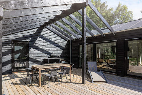 Modern patio with outdoor dining set and partial glass roof at a 5 star holiday lodge in Læsø, Denmark