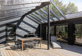 Terrasse mit modernen Gartenmöbeln und Glasdach bei einem 5-Sterne-Ferienhaus auf Læsø, Dänemark