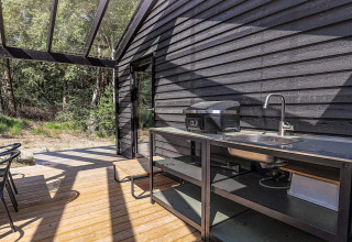 Terrasse extérieure moderne avec évier, barbecue et toit vitré d’une maison de vacances à Læsø, Danemark.