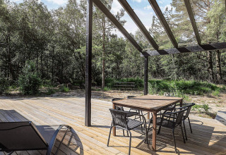 Wooden deck with dining table and chairs under a pergola at 5 star holiday home in Læsø, Denmark.