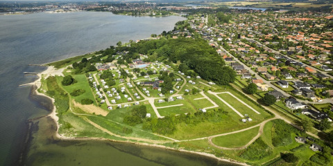 Vista aérea de Horsens City Camp en Dinamarca, mostrando parcelas de camping junto a la costa y la ciudad.