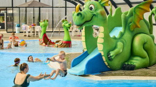 Kinderen spelen in een overdekt zwembad met groene draaischijf bij Horsens City Camp, Denemarken.