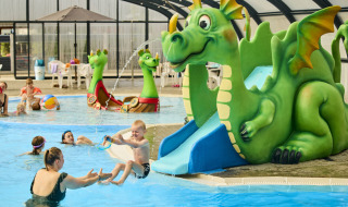 Kinderen spelen in een overdekt zwembad met groene draaischijf bij Horsens City Camp, Denemarken.