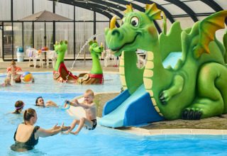 Niños juegan en una piscina cubierta con tobogán de dragón verde en Horsens City Camp, Dinamarca.
